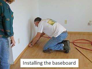 Photo of baseboard installation along a laminate floor.