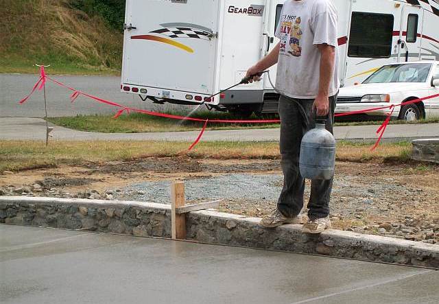 Photo of worker wetting the surface of the concrete driveway during the finishing stage.