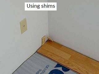 Photo showing how to use shims to tighten laminate boards on a floor.