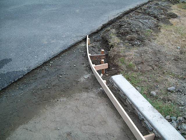 Photo of a rounded form for a concrete curb on a driveway.