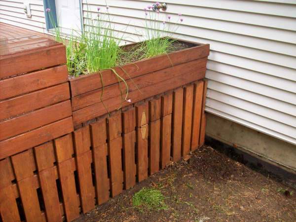 Detail of backyard wood deck showing planter on edge of deck and gate into storage area under deck.