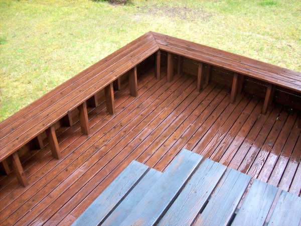 Photo of backyard wood deck showing the supports of the bench around the edge of the deck.